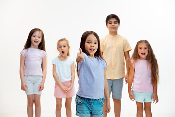 Image showing The portrait of cute little boys and girls in stylish clothes looking at camera at studio