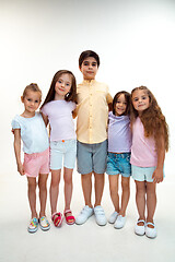 Image showing The portrait of cute little boys and girls in stylish clothes looking at camera at studio