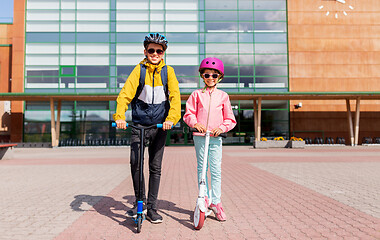 Image showing happy school children in helmets riding scooters