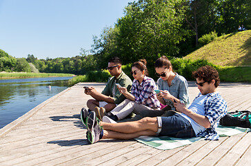 Image showing friends with smartphone on lake pier in summer