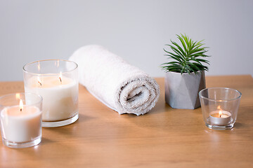 Image showing burning fragrance candles and bath towel on table