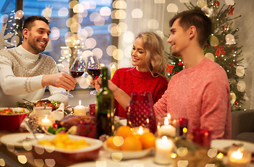 Image showing happy friends drinking red wine at christmas party