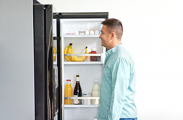 Image showing man looking for food in fridge at kitchen