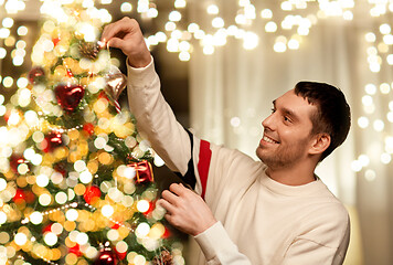 Image showing happy man decorating christmas tree at home