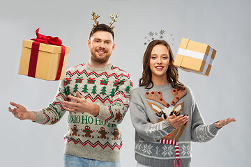 Image showing happy couple in christmas sweaters with gift boxes