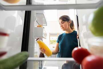 Image showing woman taking bottle of juice from fridge at home