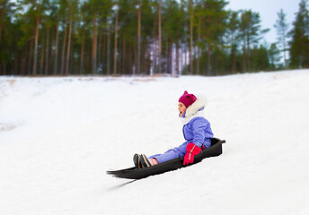 Image showing happy little girl sliding down on sled in winter