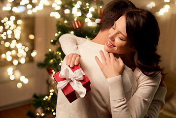 Image showing happy couple with christmas gift hugging at home