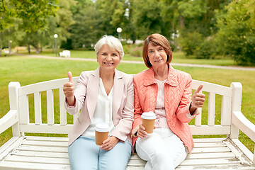 Image showing senior women with coffee showing thumbs up at park