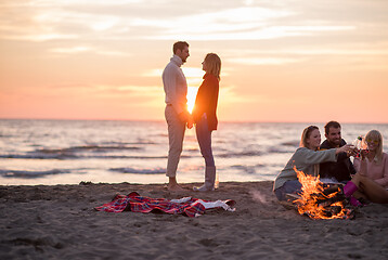 Image showing Couple enjoying with friends at sunset on the beach