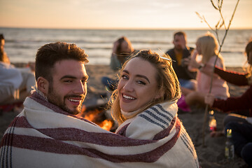 Image showing Couple enjoying with friends at sunset on the beach