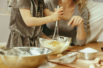 Image showing Cute little girl and her beautiful parents preparing the dough for the cake in kitchen at home