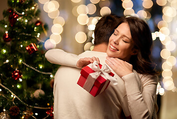 Image showing happy couple with christmas gift hugging at home