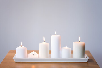 Image showing burning white candles on tray on table