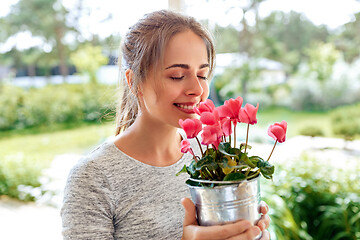 Image showing young woman with cyclamen flowers at summer garden