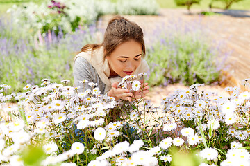 Image showing happy woman smelling chamomile flowers in garden