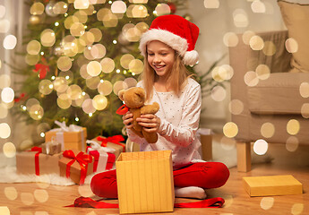 Image showing smiling girl in santa hat with christmas gift