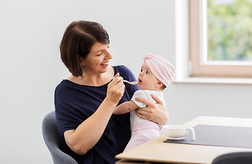 Image showing middle-aged mother feeding baby daughter at home