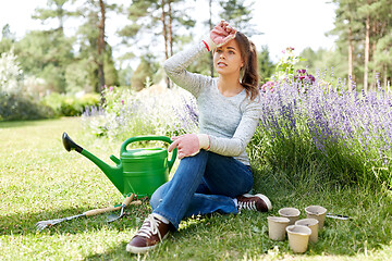 Image showing tired young woman with garden tools in summer