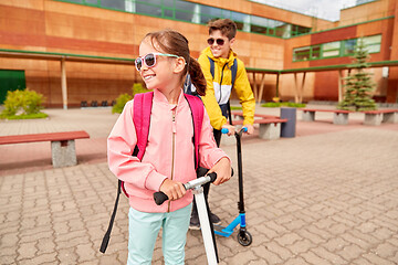 Image showing happy school children with backpacks and scooters