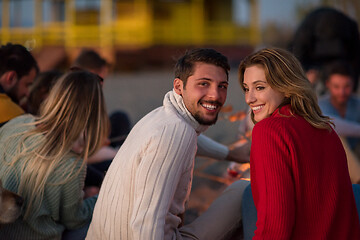 Image showing Couple enjoying with friends at sunset on the beach