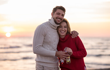 Image showing Couple hugging and drinking beer together at the beach