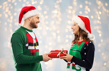 Image showing happy couple in sweaters with christmas gift