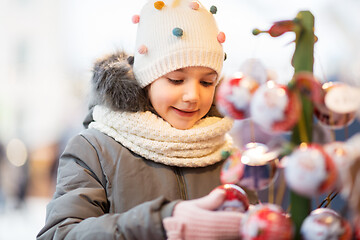 Image showing little girl choosing christmas balls at market