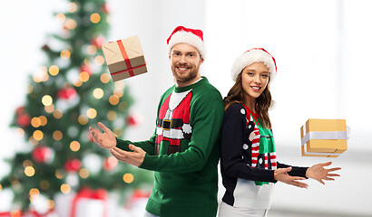 Image showing happy couple in sweaters with christmas gifts