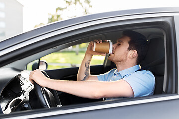 Image showing tired man driving car and drinking coffee