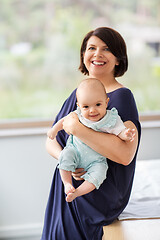 Image showing middle-aged mother holding baby daughter at home