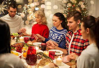 Image showing friends having home christmas dinner and praying