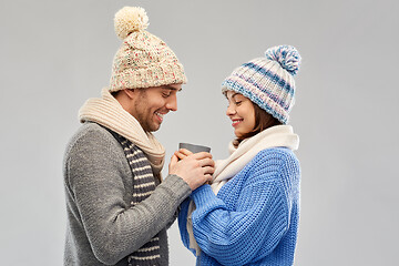 Image showing happy couple in winter clothes holding one cup