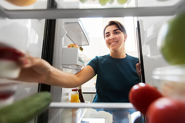 Image showing happy woman taking food from fridge at home