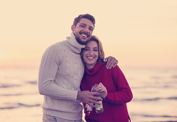 Image showing Couple hugging and drinking beer together at the beach