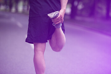 Image showing male runner warming up and stretching before morning training