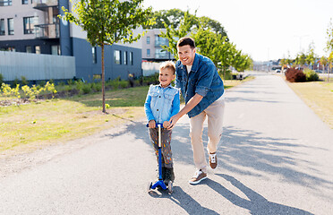 Image showing happy father and little son riding scooter in city