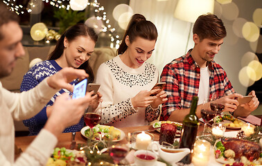 Image showing friends with smartphones having christmas dinner