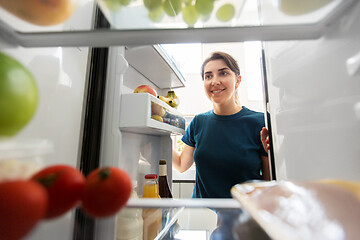 Image showing happy woman at open fridge at home kitchen