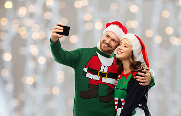 Image showing happy couple in christmas sweaters taking selfie