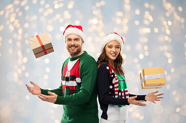 Image showing happy couple in sweaters with christmas gifts