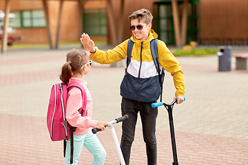 Image showing happy school children with backpacks and scooters