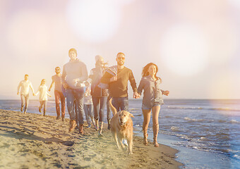 Image showing Group of friends running on beach during autumn day