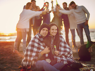 Image showing Couple enjoying with friends at sunset on the beach