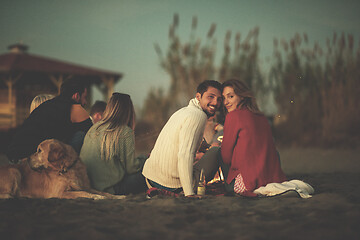 Image showing Couple enjoying with friends at sunset on the beach