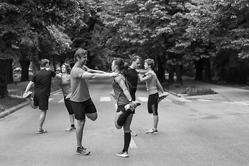 Image showing runners team warming up and stretching before morning training