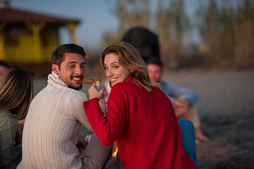 Image showing Couple enjoying with friends at sunset on the beach