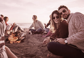 Image showing Couple enjoying with friends at sunset on the beach