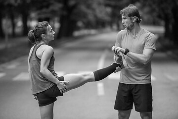 Image showing runners team warming up and stretching before morning training