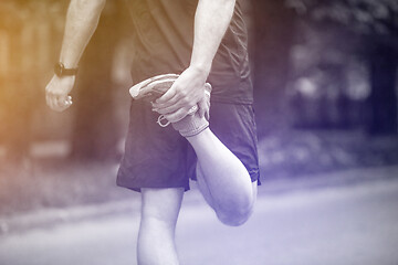 Image showing male runner warming up and stretching before morning training